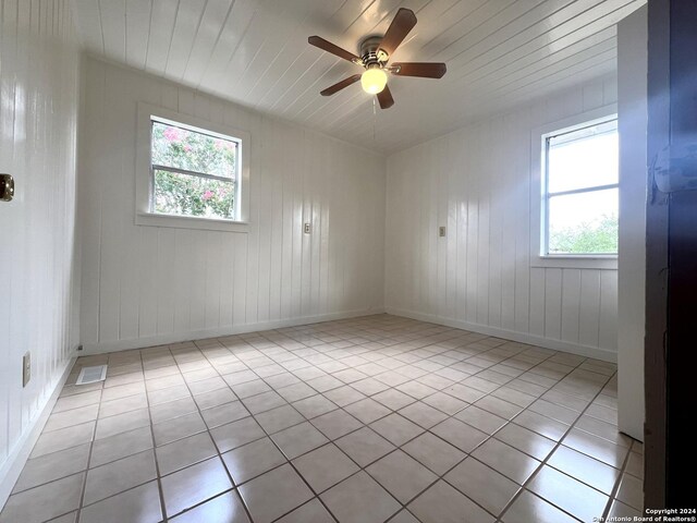 tiled empty room featuring ceiling fan and wooden ceiling