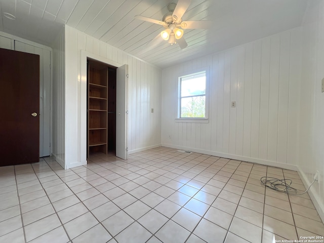 unfurnished bedroom featuring a spacious closet, a closet, ceiling fan, and light tile patterned flooring