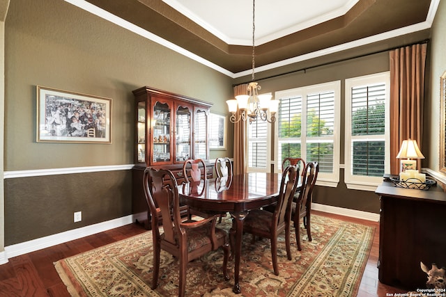 dining room with hardwood / wood-style flooring, a raised ceiling, an inviting chandelier, and ornamental molding