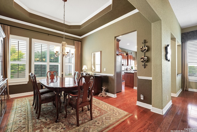 dining room featuring crown molding, an inviting chandelier, dark hardwood / wood-style floors, and a tray ceiling