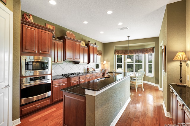 kitchen with sink, wood-type flooring, decorative backsplash, and stainless steel appliances