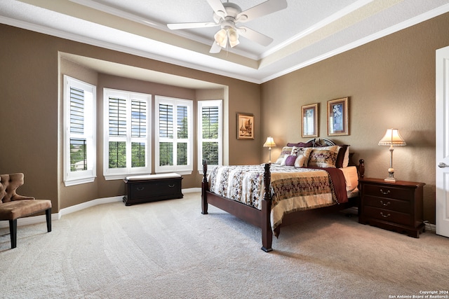 carpeted bedroom featuring ceiling fan, crown molding, and a tray ceiling