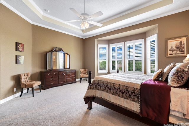 bedroom with ceiling fan, carpet flooring, crown molding, and a tray ceiling