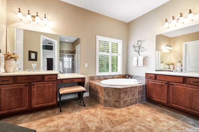 bathroom featuring a relaxing tiled tub, double sink vanity, and tile patterned floors