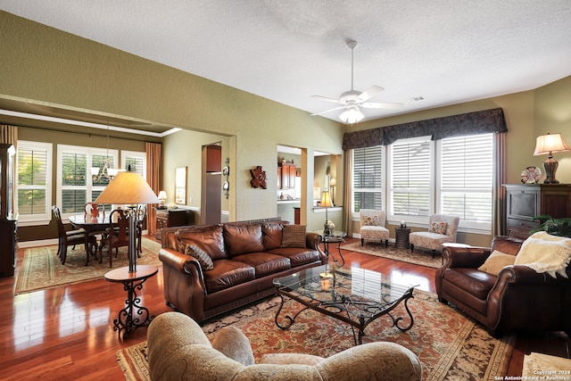 living room featuring ceiling fan, a textured ceiling, and wood-type flooring