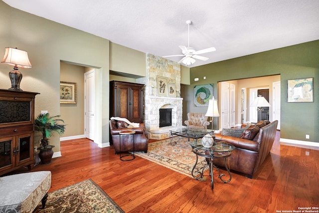 living room with ceiling fan, a fireplace, and wood-type flooring