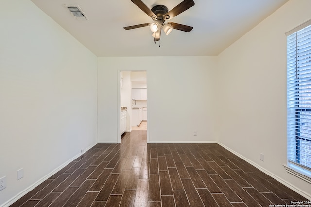 empty room with a wealth of natural light, ceiling fan, and dark hardwood / wood-style floors