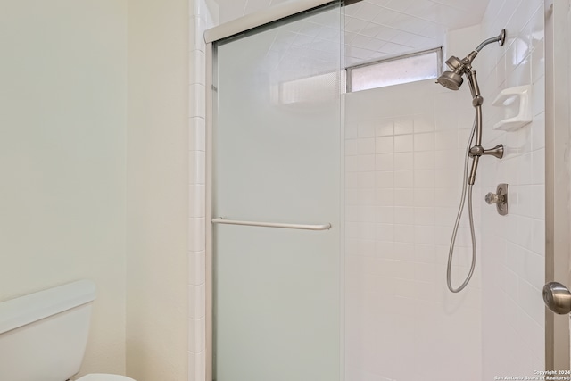 bathroom featuring a shower with shower door and toilet