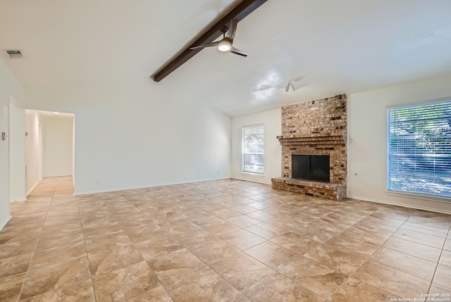 unfurnished living room with light tile patterned floors, lofted ceiling with beams, a healthy amount of sunlight, and brick wall