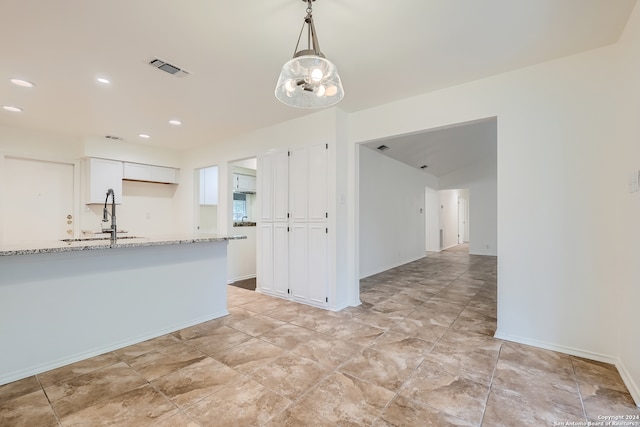 kitchen featuring light tile patterned floors, sink, pendant lighting, and light stone countertops