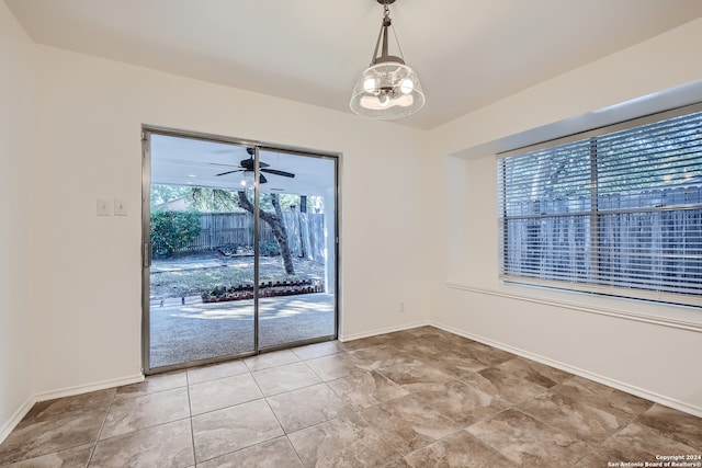 spare room featuring ceiling fan with notable chandelier and tile patterned floors