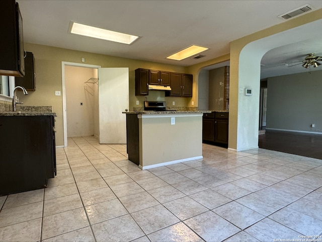 kitchen featuring dark brown cabinets, range, light stone countertops, light tile patterned floors, and ceiling fan