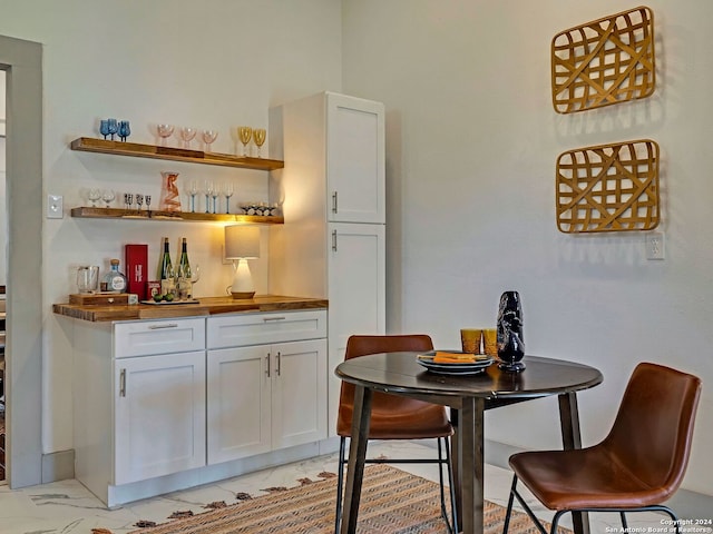 interior space with light tile patterned floors, wooden counters, and white cabinets