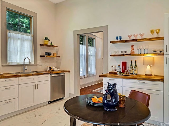 kitchen featuring a wealth of natural light, dishwasher, wood counters, and white cabinets