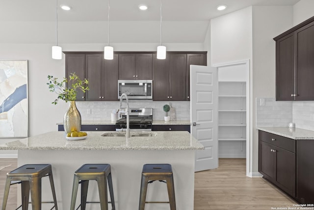 2039 Newforest Peak, New Braunfels, TX 78130 - kitchen featuring stainless steel appliances, a kitchen breakfast bar, dark brown cabinetry, backsplash, and a sink