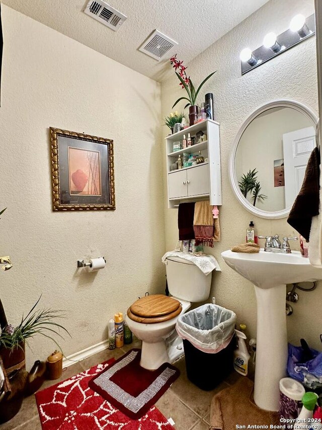 bathroom with toilet, a textured ceiling, and tile patterned flooring