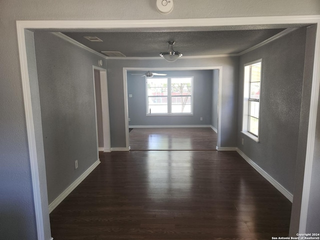 empty room featuring dark wood finished floors, crown molding, and baseboards