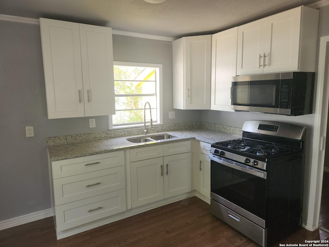 kitchen featuring dark wood-style flooring, appliances with stainless steel finishes, white cabinets, and a sink