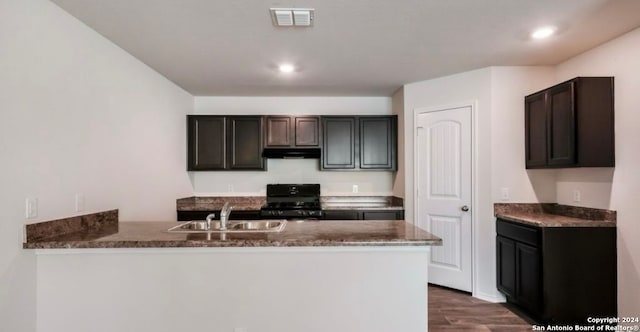 kitchen featuring hardwood / wood-style floors, dark brown cabinets, sink, range, and kitchen peninsula