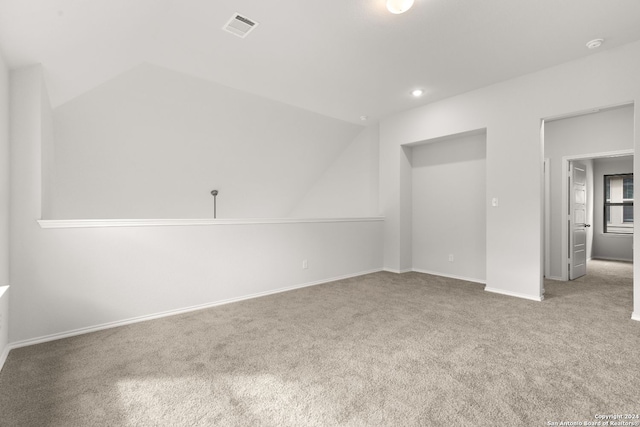 carpeted empty room featuring lofted ceiling