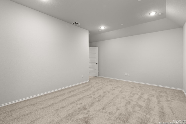 carpeted empty room featuring vaulted ceiling