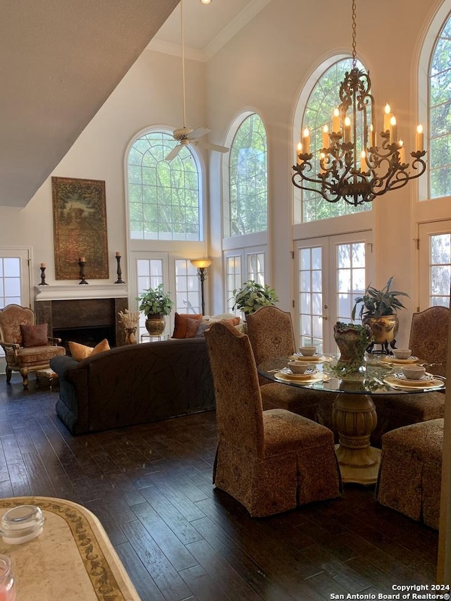 dining area with dark wood-style floors, ornamental molding, french doors, a fireplace, and high vaulted ceiling