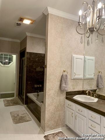 bathroom with a chandelier, vanity, tile patterned floors, shower with separate bathtub, and crown molding