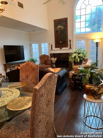 living room with a high ceiling, ceiling fan, hardwood / wood-style flooring, and french doors