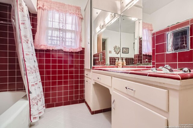 bathroom with shower / tub combo with curtain, tile walls, vanity, and tile patterned floors