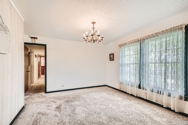 spare room featuring carpet, an inviting chandelier, and crown molding