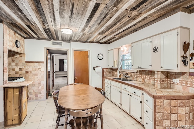 kitchen with backsplash, tile counters, white cabinets, light tile patterned floors, and sink