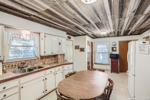 kitchen featuring white cabinetry, white refrigerator, decorative backsplash, and a healthy amount of sunlight