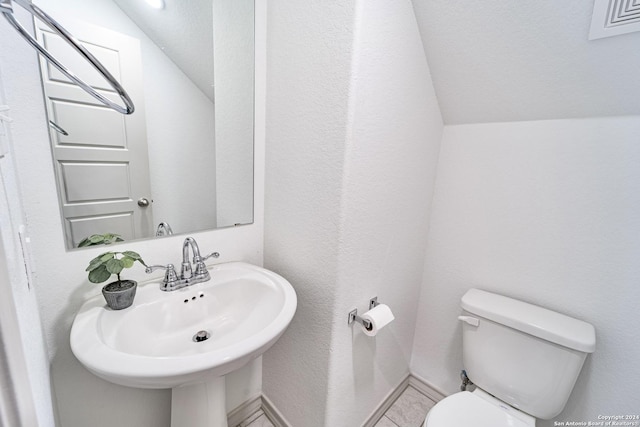 bathroom featuring toilet, baseboards, a sink, and lofted ceiling