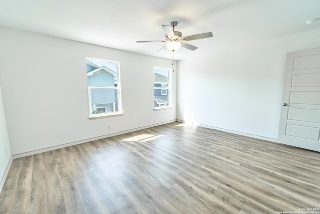 unfurnished room with ceiling fan, light wood finished floors, and baseboards