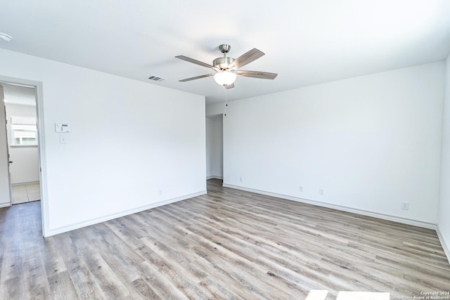 spare room with visible vents, light wood finished floors, a ceiling fan, and baseboards