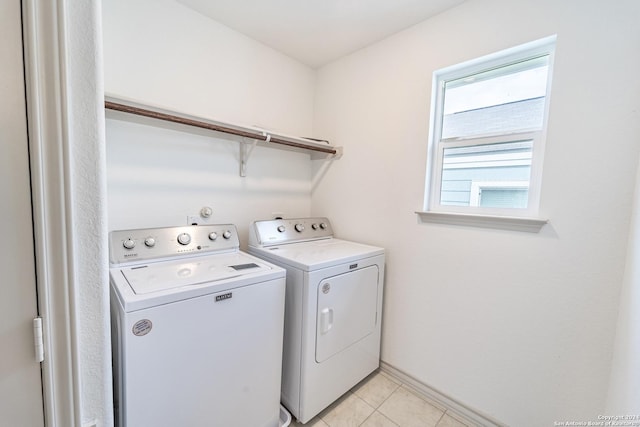 laundry area with laundry area, light tile patterned flooring, washing machine and clothes dryer, and baseboards