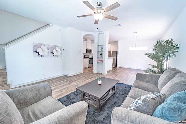 living room with ceiling fan with notable chandelier and light hardwood / wood-style floors