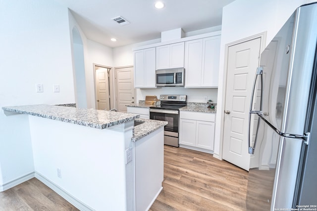 kitchen with white cabinets, light stone countertops, kitchen peninsula, and appliances with stainless steel finishes