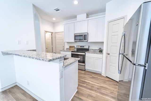 kitchen with a peninsula, visible vents, appliances with stainless steel finishes, and white cabinets