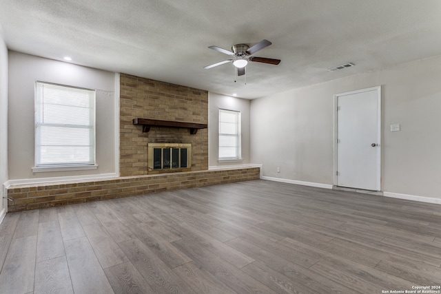 unfurnished living room featuring ceiling fan, wood-type flooring, and a fireplace