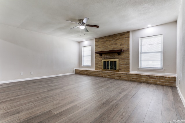 unfurnished living room with ceiling fan, hardwood / wood-style flooring, plenty of natural light, and a brick fireplace