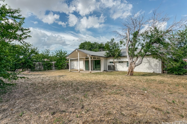 back of property with central air condition unit and a lawn