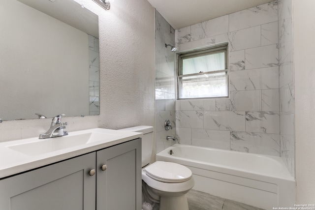 full bathroom with tile patterned flooring, toilet, tiled shower / bath, and vanity