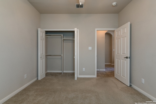 unfurnished bedroom with light colored carpet and a closet