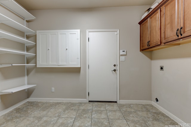 clothes washing area featuring light tile patterned flooring, cabinets, and hookup for an electric dryer