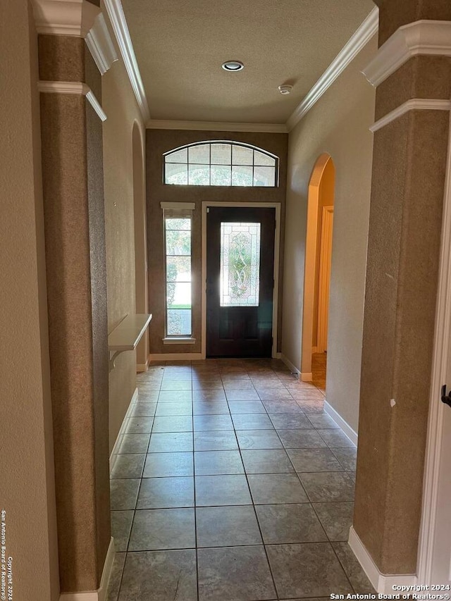 tiled foyer entrance featuring a textured ceiling and crown molding