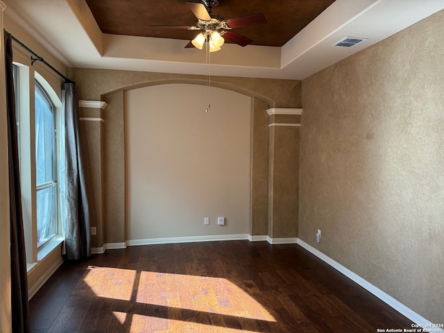 unfurnished room featuring a tray ceiling and dark wood-type flooring