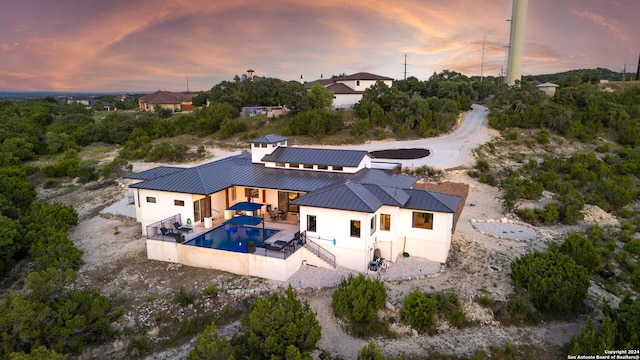 exterior space with fence, metal roof, a patio area, an outdoor pool, and a standing seam roof