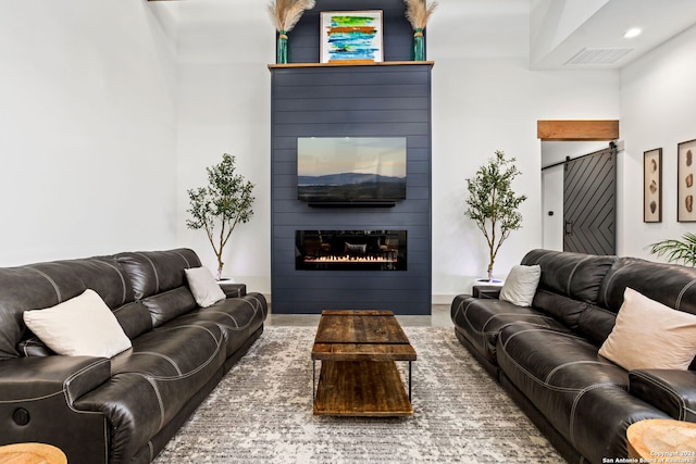 living room featuring a barn door, a fireplace, and visible vents