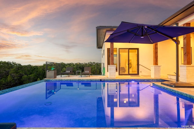 pool at dusk with an infinity pool and a patio